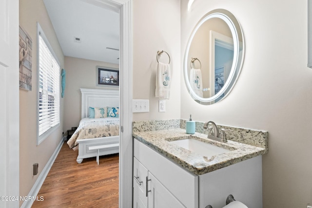 ensuite bathroom with baseboards, visible vents, wood finished floors, ensuite bathroom, and vanity