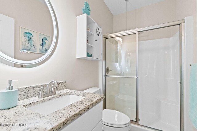 bathroom featuring vanity, toilet, and a shower with shower door