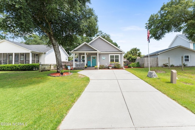 view of front of home featuring covered porch, fence, a front lawn, and concrete driveway