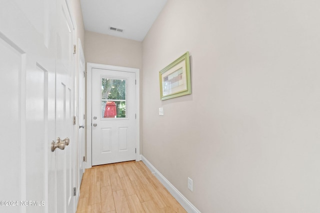 doorway with visible vents, light wood finished floors, and baseboards