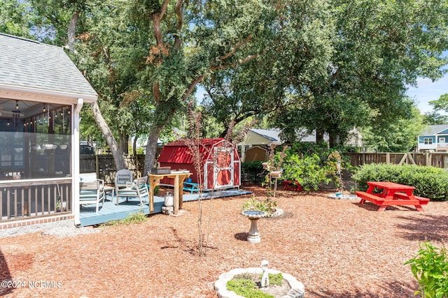 view of yard featuring a storage shed, a sunroom, a fenced backyard, an outbuilding, and a wooden deck