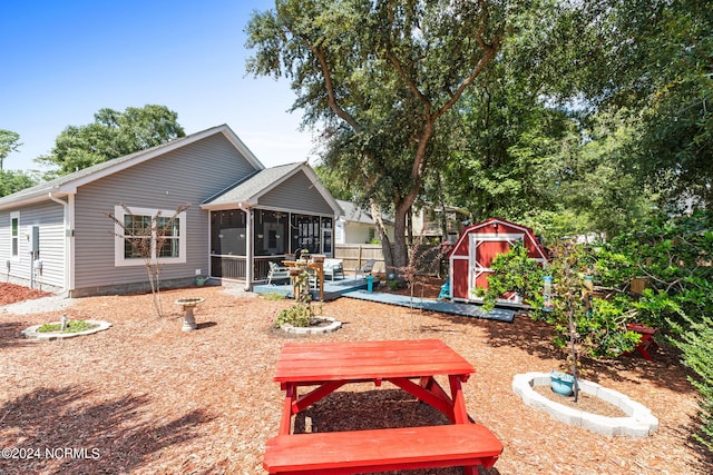 rear view of property featuring a patio, a shed, and a sunroom