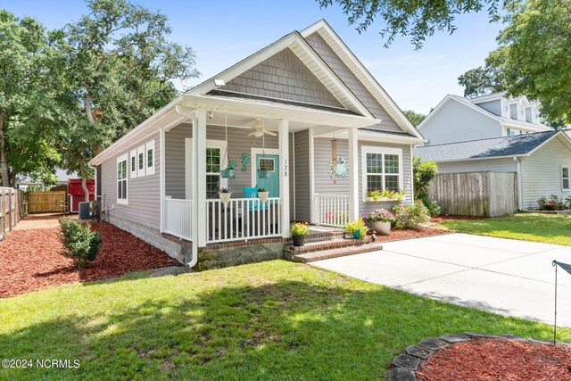 view of front facade with central air condition unit, covered porch, and a front yard