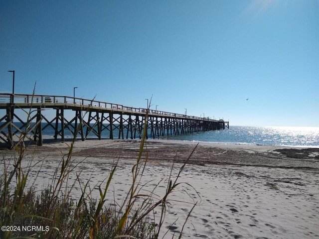 view of dock featuring a water view and a beach view