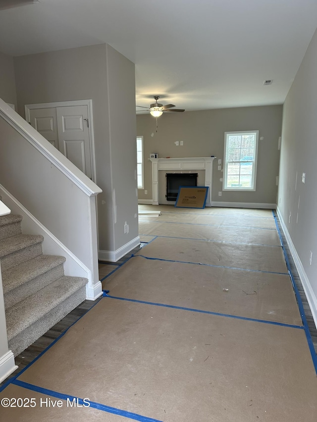 unfurnished living room with ceiling fan and a fireplace