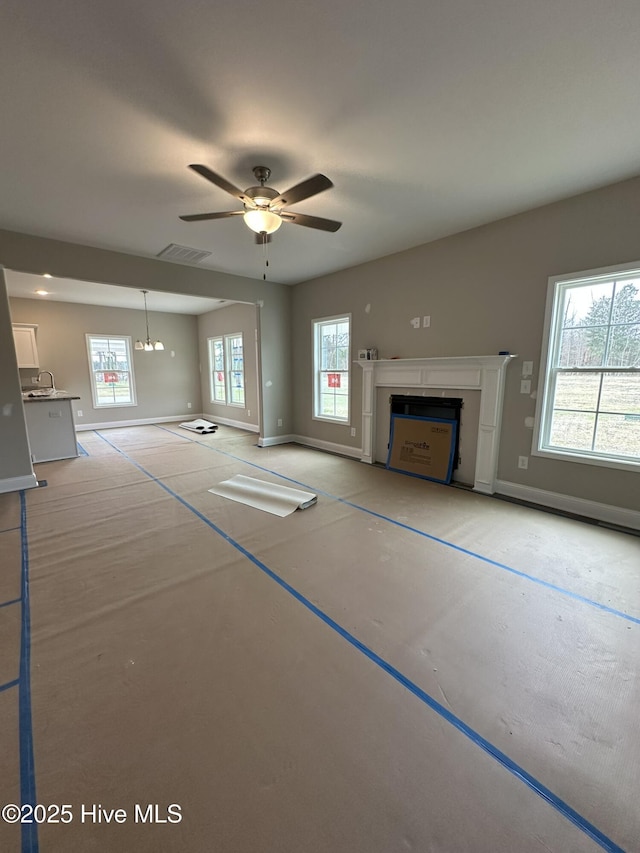 unfurnished living room with ceiling fan with notable chandelier