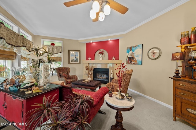 living room with crown molding, ceiling fan, a tiled fireplace, and light colored carpet