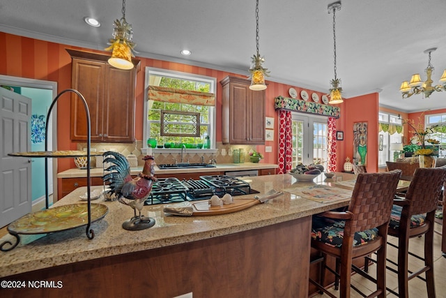 kitchen featuring light stone counters, decorative light fixtures, crown molding, and tasteful backsplash