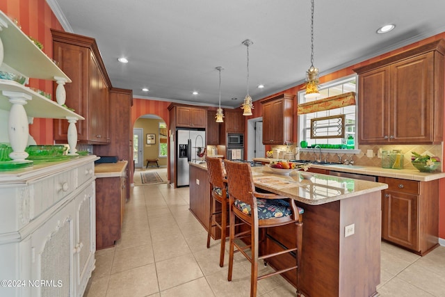 kitchen with a breakfast bar, stainless steel appliances, an island with sink, and hanging light fixtures