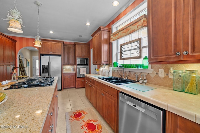 kitchen with pendant lighting, ornamental molding, light tile patterned floors, sink, and appliances with stainless steel finishes