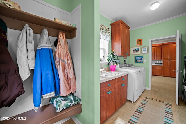 laundry area with light tile patterned floors, independent washer and dryer, crown molding, and cabinets