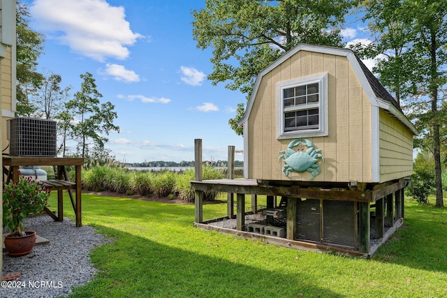 view of yard featuring a water view, an outbuilding, and central AC