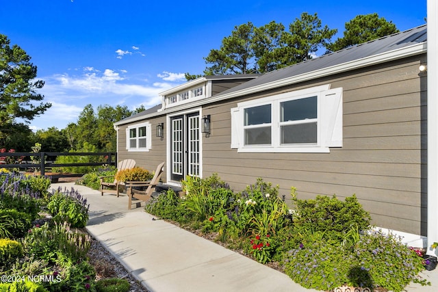 view of exterior entry with fence, metal roof, a patio, and french doors