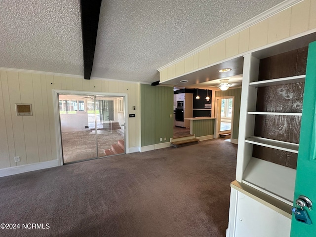 interior space featuring a wealth of natural light, ceiling fan, a textured ceiling, and beamed ceiling