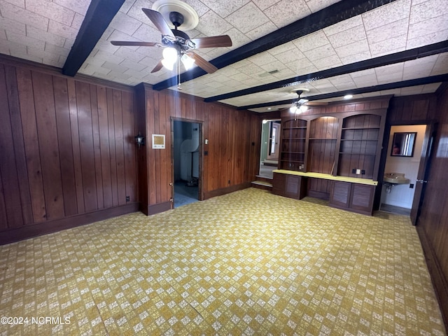 interior space with wood walls, ceiling fan, and sink