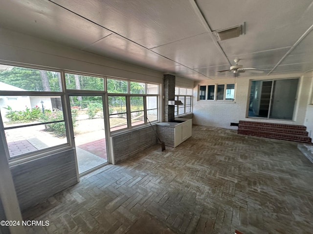 unfurnished sunroom with ceiling fan and plenty of natural light