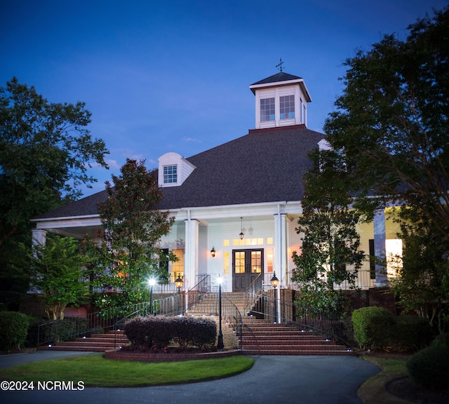 view of front of house featuring covered porch, french doors, and stairs