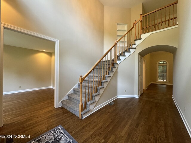 stairway with hardwood / wood-style floors and a high ceiling