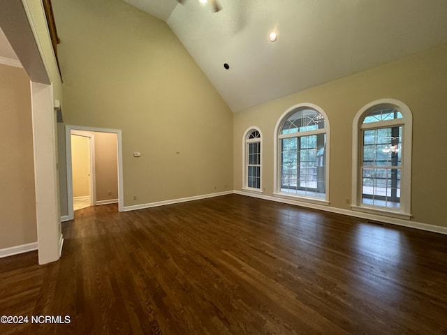 unfurnished living room featuring high vaulted ceiling, dark wood finished floors, and baseboards