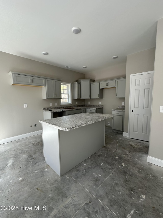 kitchen featuring gray cabinetry, light stone counters, and a center island