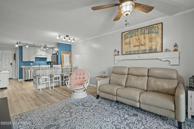 living room featuring a textured ceiling, ceiling fan, and light wood-type flooring