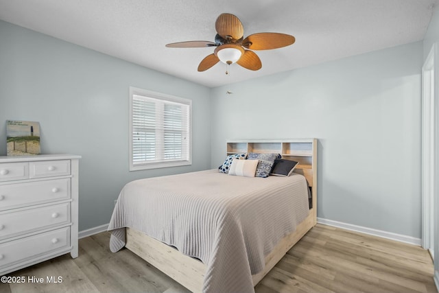 bedroom featuring ceiling fan, light wood-style flooring, and baseboards