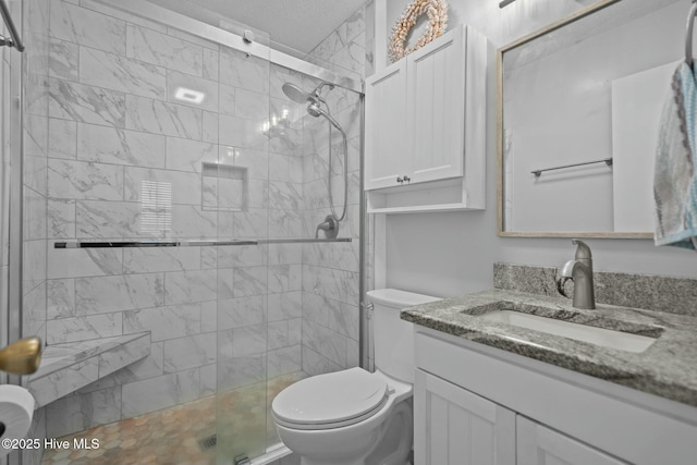 bathroom with toilet, a tile shower, and vanity