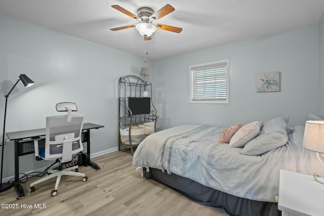 bedroom featuring a textured ceiling, light wood-type flooring, a ceiling fan, and baseboards