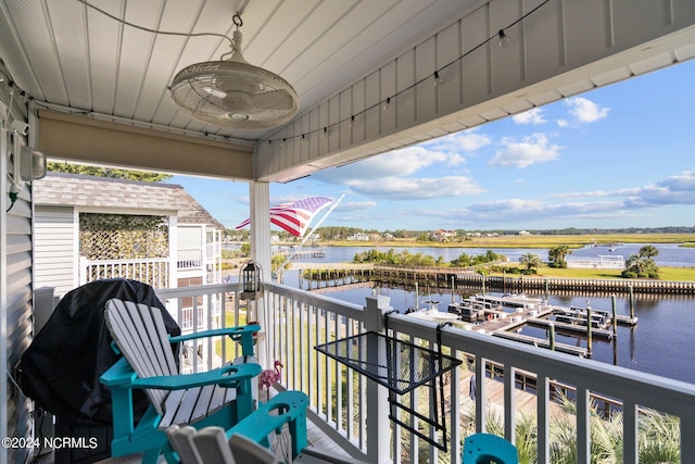 balcony with a ceiling fan, a dock, and a water view