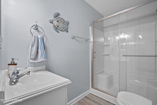 bathroom with hardwood / wood-style floors, vanity, a textured ceiling, toilet, and a shower with door