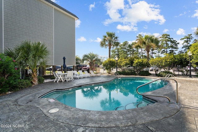 community pool with fence and a patio