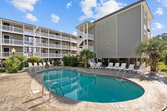 community pool with a patio area and fence