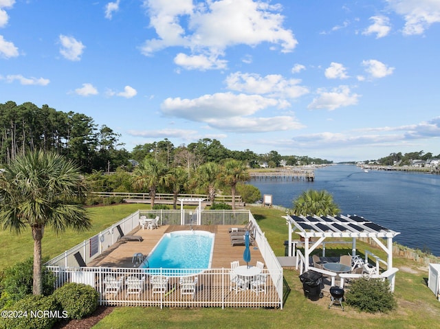 pool with a yard, a deck with water view, fence, and a pergola