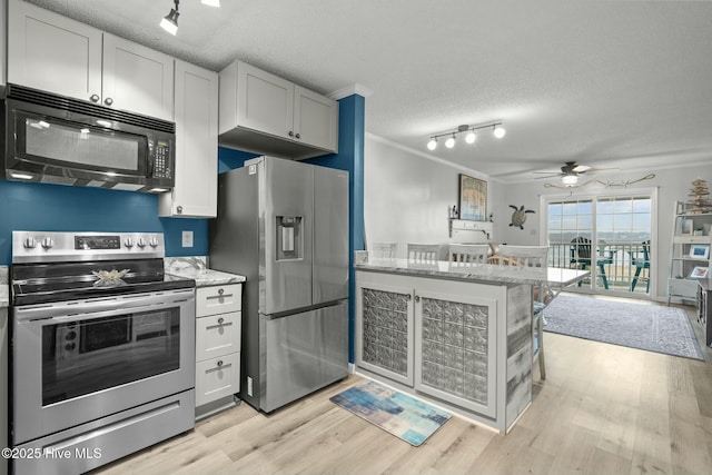 kitchen featuring light stone counters, crown molding, stainless steel appliances, light wood-style floors, and a textured ceiling