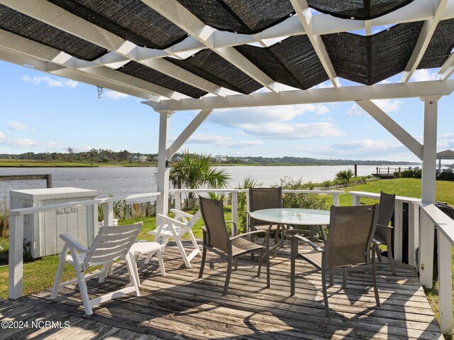 wooden terrace featuring a water view and outdoor dining space