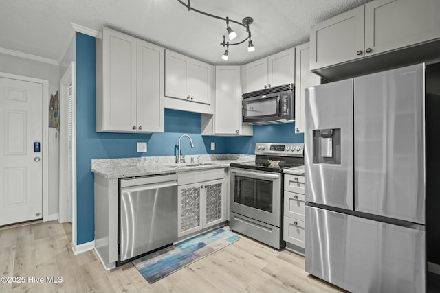 kitchen featuring sink, appliances with stainless steel finishes, rail lighting, light hardwood / wood-style flooring, and a textured ceiling