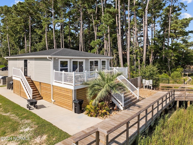 view of front of house with roof with shingles, stairs, a deck, and a patio