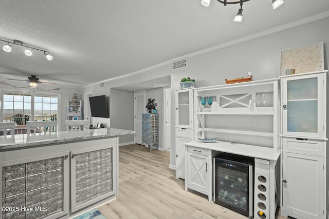 kitchen with crown molding, light wood finished floors, wine cooler, and white cabinets