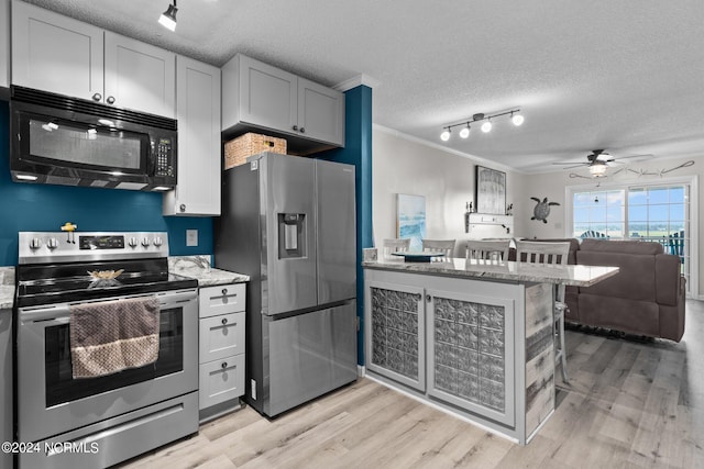 kitchen featuring appliances with stainless steel finishes, light hardwood / wood-style floors, ornamental molding, a textured ceiling, and track lighting