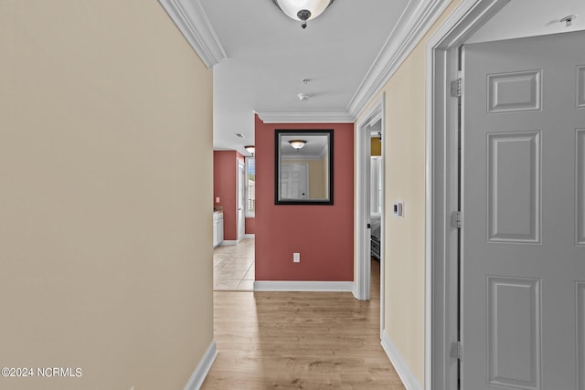 corridor featuring ornamental molding, light wood-type flooring, and baseboards