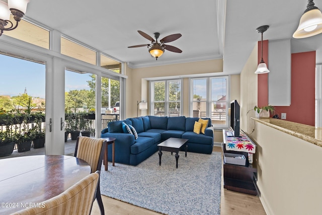 living area featuring crown molding, ceiling fan, a wall of windows, light wood-type flooring, and baseboards