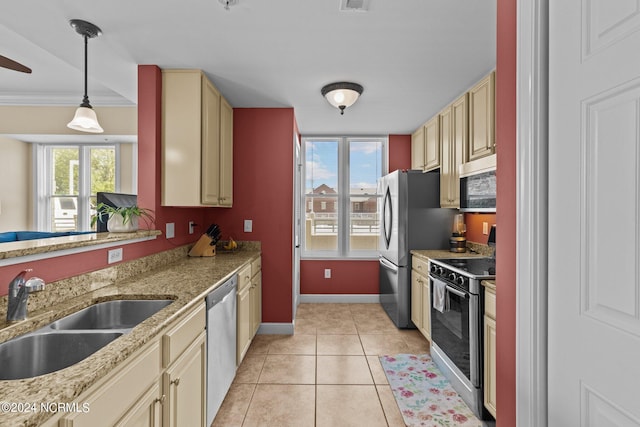 kitchen with stainless steel appliances, light tile patterned flooring, a sink, and cream cabinets