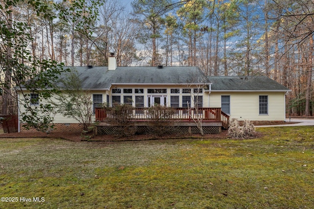 back of property with a chimney, a lawn, a deck, and crawl space