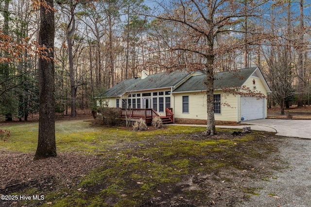 ranch-style home with driveway, a front yard, and a wooden deck