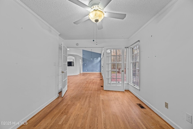 spare room with visible vents, crown molding, a textured ceiling, and light wood finished floors