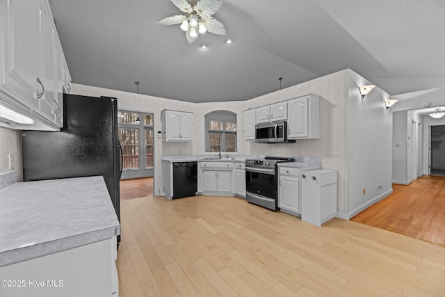 kitchen with white cabinets, vaulted ceiling, stainless steel appliances, light countertops, and a sink