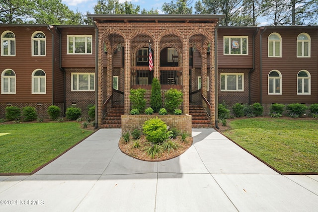 view of front facade with crawl space, a front yard, and brick siding