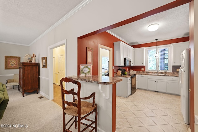 kitchen featuring stainless steel microwave, black range with electric stovetop, freestanding refrigerator, a sink, and a peninsula