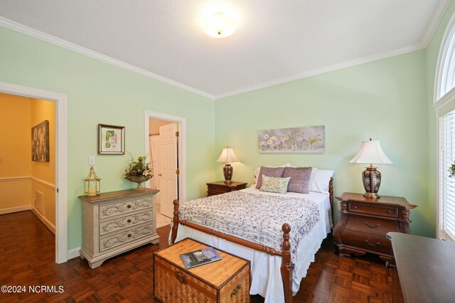 bedroom with ensuite bath, ornamental molding, and dark parquet flooring