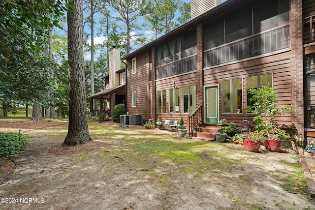 back of property featuring entry steps, central air condition unit, and a chimney